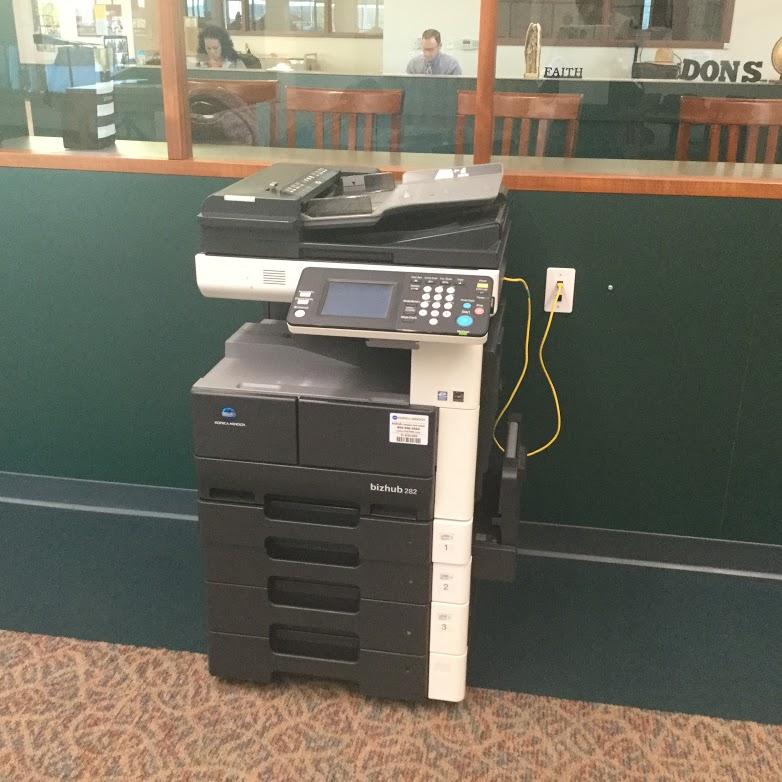 The printer is located in the front corner of the library behind the flag.