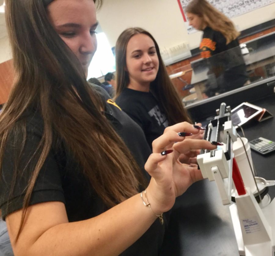 Delaney Fritz 20 and Anna Fogarty 20 calculate the mass of a calorimeter in Mrs. Kay Dunns chemistry class, as students practice finding the specific heat capacity of different metals. 
