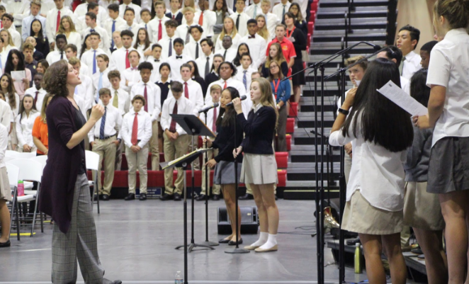 Ms. Swift directs the student choir at Mass on Wednesday, as the musicians wrap up their final song. 
