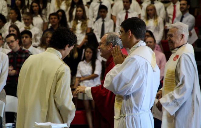 Fr. Patrick Wainwright opens Wednesday’s school mass with a welcoming prayer, surrounded by fellow priests enjoying the celebration of Christ. 
