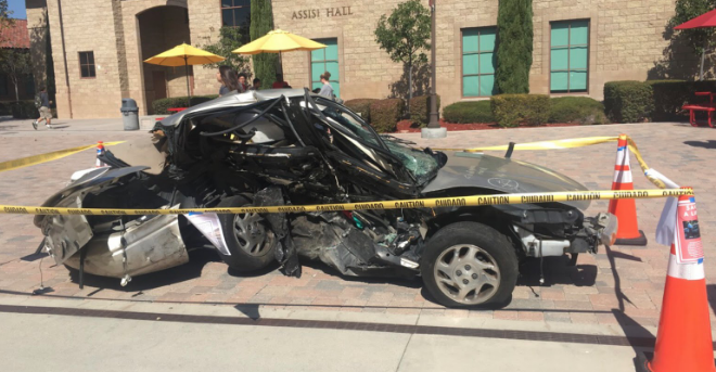 Students walk past a wrecked car on display during Red Ribbon Week at Cathedral Catholic High School. The car was on display all this week to show the dangers of driving under the influence of drugs and alcohol, a theme in the observation of Red Ribbon Week. 
