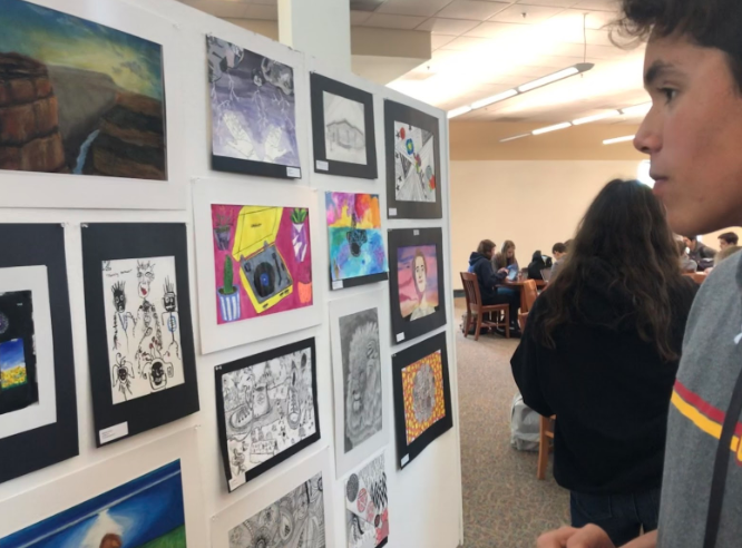 Carlos Munoz ‘21 admires the art showcase put up in the Academic Center by the art teachers. The art showcase accompanies the music showcase performance at the Cathedral Catholic High School theater Wednesday, May 22.

