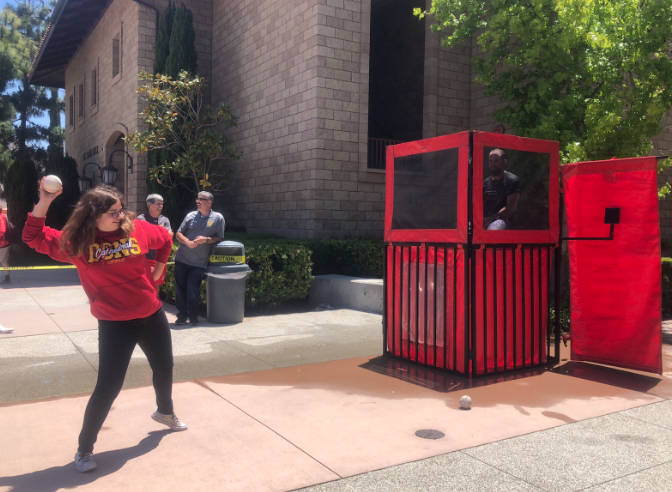 During Cathedral Catholic High School’s annual spring carnival, CCHS student Nicole Izzo ‘21, with a strong throwing arm, attempts to send Coach Jeremy Petitte falling into the freezing water at the dunk tank. 

