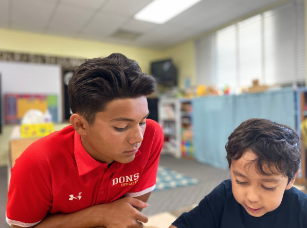 Julian Ong ‘22 listens intently as an elementary student from Our Lady’s School reads to him Wednesday. As part of the sophomores’ service trip, they assisted and interacted with students from Nativity Prep, Our Lady’s School, St. Katherine Drexel, and St. Rita’s schools. Students participate in groups with members of their fellow grade levels throughout the year to help and interact with the community.