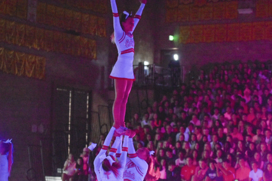 Kelley Hallinan (top) performs a routine with the rest of the cheer squad along with the rest of the cheer team, showcasing their talent through various stunts and dances.