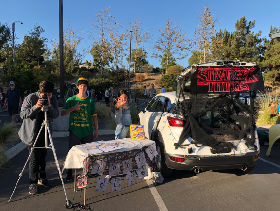 Trunk-or-Treat enabled Cathedral Catholic High School clubs and academic honor societies to share festivities with the community. Nico Martinez ‘21, Daniel Pedler ‘21, and Ariella Pacheco ‘21 showcase photography club with a Stranger Things-themed booth. 