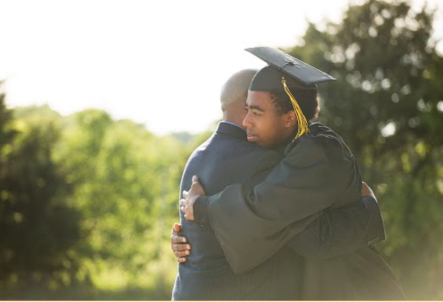 A father and son embrace during Graduation. For many families, this moment is transformational and one that required an immense amount of sacrifice. 