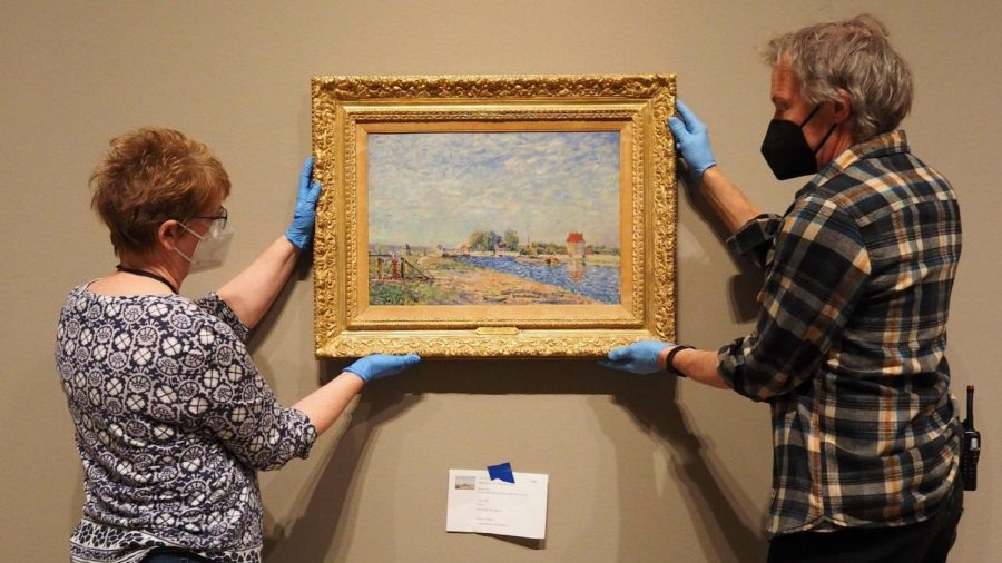 Two individuals work to install one of the gallery’s latest newest art pieces, from an exhibit entitled Monet to Matisse. People can view this stunning piece and so many more through October 10th.