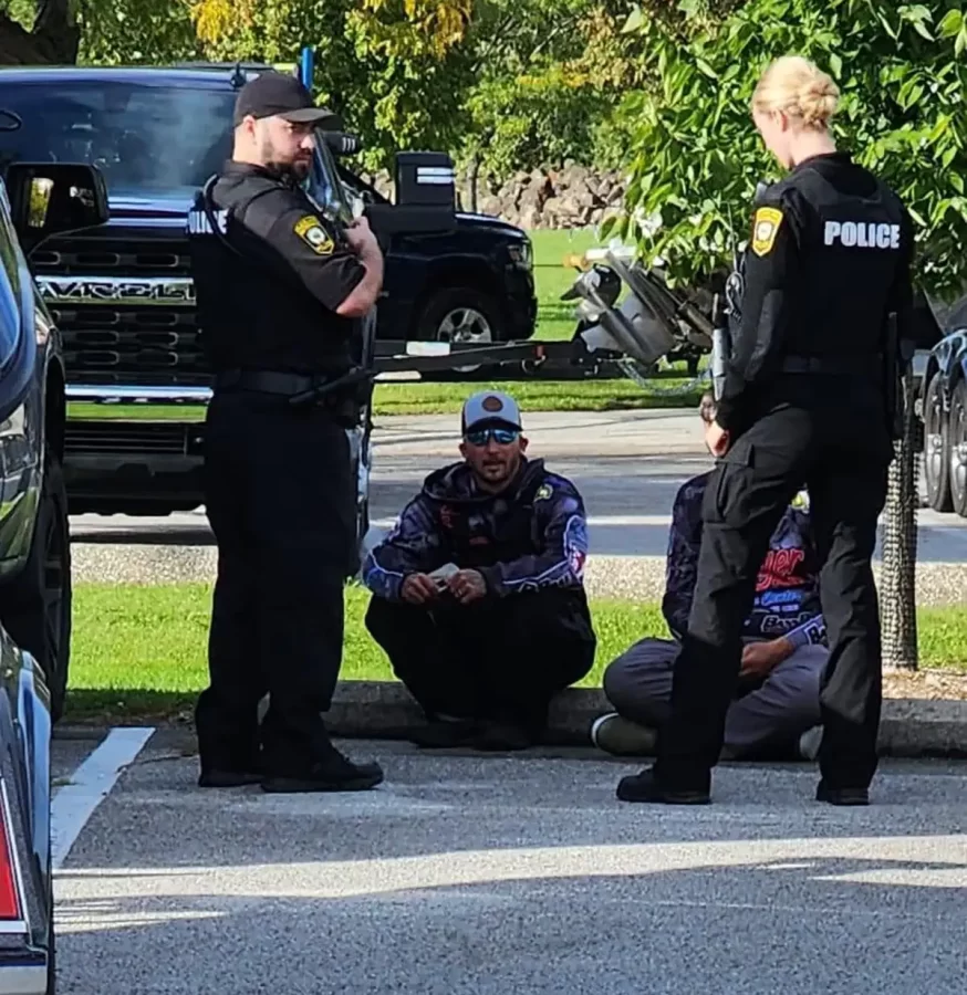 Jacob Runyan and Chase Cominsky sit in shame as they are protected by police. The two cheaters are at the center of outrage in the fishing community.